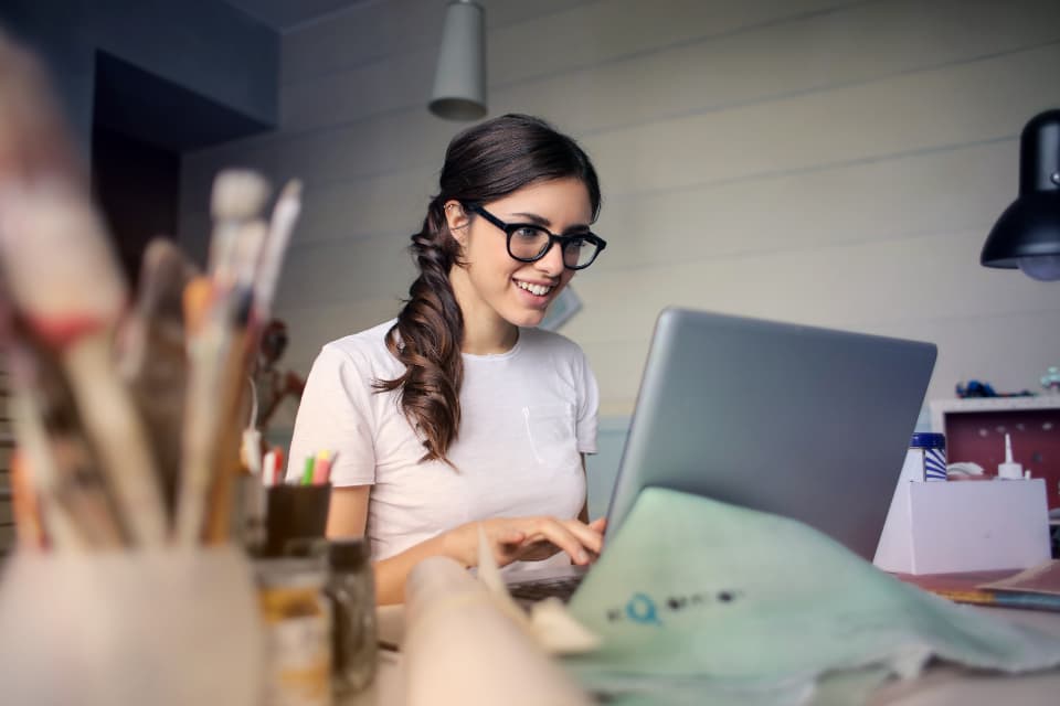 Frau mit Brille arbeitet lächelnd am Laptop